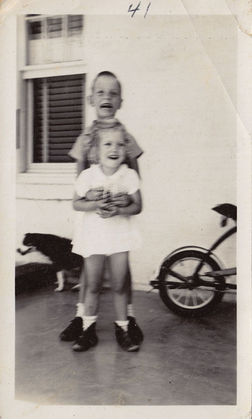 1941, April: Wally and Kathy on front porch with dog and bike.